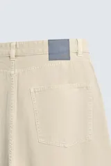 Pantalón de jean blanco, corte holgado y amplio en toda la pierna, tiro medio, tejido ligero, cinco bolsillos, efecto lavado y cierre frontal con cremallera y botón.