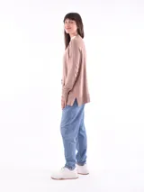 Saco color beige de tejido de punto, con cuello abierto, bolsillos frontales y mangas largas con detalle de botones en los puños.