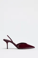 Zapato destalonado acharolado color borgoña, con escote en pico, cierre con tira trasera ajustable, tacón fino y punta fina.