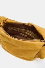 Bolso de mano color mostaza, de serraje, con asa ancha con detalles y cierre mediante hebilla metálica.