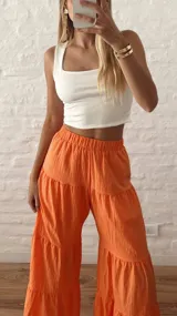 Pantalón palazzo naranja con elástico en la cintura y diseño escalonado con volados.