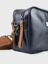 Bandolera de cuero color marrón con correa ajustable y logo de la marca en el frente.