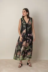 Vestido largo negro con estampado de hojas y flores en tonos marrones, verdes y rosados. Tiene escote en V y corte evasé.