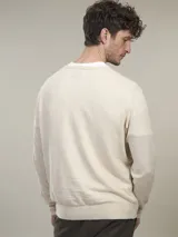 Sweater de punto color beige claro, de corte clásico y cuello redondo.