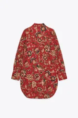 Camisa larga de algodón con estampado floral en tonos rojos, marrones y verdes. Tiene cuello solapa, manga larga con puños y bajo redondeado.
