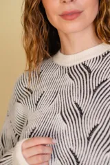 Buzo tejido color blanco con diseño en relieve de líneas verdes.