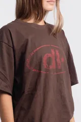 Remera marrón de corte holgado con estampado de elipse y estrella en color rojo.