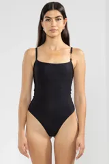 Traje de baño enterizo negro con breteles finos y detalle de cadena dorada en uno de los hombros.