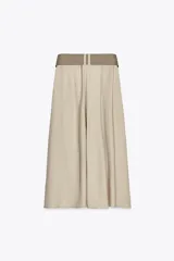 Falda midi color beige con textura rústica, tiro alto, pinzas delanteras, corte evasé y cinturón ancho con hebilla metálica.