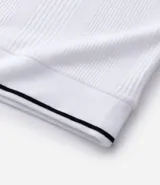 Remera polo blanca de media malla texturizada a rayas, corte regular, con cuello y mangas cortas en ribana con detalle contrastante en negro.