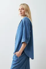 Camisa de jean celeste de corte recto, con cuello mao, mangas cortas y cierre frontal con botones.