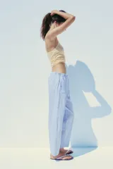 Pantalón tipo barrel con rayas verticales celestes y blancas, tiro medio y cintura elástica ajustable con lazo. Tiene bolsillos laterales y falsos bolsillos de vivo en la espalda.