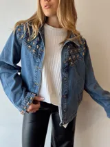 Campera de jean celeste con apliques de estrellas doradas en cuello, hombros y puños.