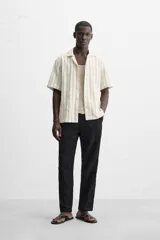 Camisa de manga corta con cuello bowling y corte relaxed fit, confeccionada en tejido con algodón y diseño a rayas verticales en tonos beige y blanco.