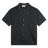 Camisa de punto de manga corta color negro, con cuello tipo camp y botones frontales. Presenta detalles de bordados tonales con motivos botánicos y franjas verticales texturizadas.