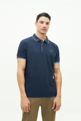 Polo color beige con textura, corte regular, logo estampado en el pecho y mangas cortas con ribete blanco.
