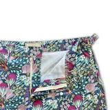 Short de baño con estampado floral en tonos violeta, azul y blanco. Cuenta con pretina fija con hebillas metálicas laterales, botón a presión, cierre frontal, tres bolsillos y mesh interior hipoalergénico.