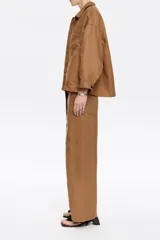 Pantalón blanco de lino y algodón, corte barrel, largo tobillero, con cierre frontal oculto, bolsillos delanteros y traseros, y cinturón de tela a tono.