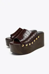 Mules con plataforma de madera y capellada marrón con textura de piel de cocodrilo.