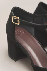 Zapato de vestir negro de cuero, con punta fina, tira en forma de T y hebilla lateral.