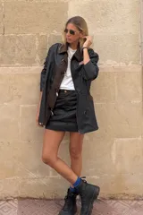 Minifalda negra de cuero sintético con costuras marrones.