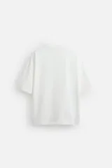 Camiseta blanca de corte relaxed fit, cuello redondo y manga corta. Estampado combinado a contraste en el delantero con imagen borrosa de flor y texto en azul.