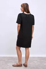 Vestido corto negro de lino con escote en V y abotonadura frontal.
