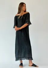 Vestido largo negro con escote off-shoulder, mangas 3/4 con volados y ruedo con flecos.