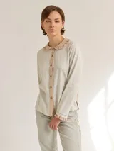 Camisa blanca de algodón con cuello redondo, manga larga y cierre frontal con botones.