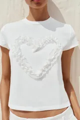 Camiseta blanca de algodón con cuello redondo, manga corta y detalle de corazón con tejido en relieve en el delantero.