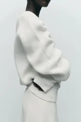 Sweater color blanco de punto perlado, con cuello redondo y mangas largas.