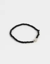Pulsera elástica de mostacillas negras con dije de corazón plateado.