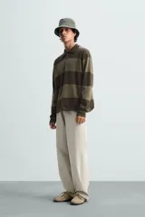 Polo relaxed fit de punto tejido en hilatura de algodón, a rayas horizontales en tonos azul y negro. Cuello solapa con cierre frontal de botonadura, manga larga y acabados en rib.