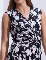 Vestido largo sin mangas, con escote en V cruzado y estampado floral en blanco sobre fondo negro.
