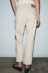 Jeans de tiro medio color beige, corte cigarette, con cinco bolsillos y cierre frontal de cremallera y botón.