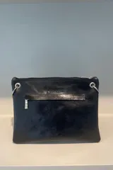 Sobre de cuero vacuno color bordó, con diseño frontal decorado con múltiples ojalillos metálicos plateados dispuestos en cuatro círculos. Cuenta con cierre superior y correa larga ajustable para llevar al hombro o cruzada.