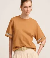 Blusa boxy de mangas cortas amplias, confeccionada en algodón, con cuello redondo y detalle de entremedios en las mangas.