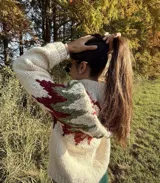 Sweater de lana color crudo con cuello alto y diseño geométrico en tonos verde y bordó.