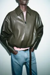 Chaqueta estilo bomber de efecto piel en color verde oliva, con cuello solapa, cierre frontal con cremallera, mangas largas y bajo con acabado elástico.