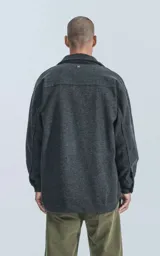 Chaqueta gris de paño con cuello clásico, cierre frontal con botones, bolsillos laterales y corte recto.