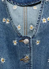 Chaleco denim con bordado de margaritas, corte crop, cuello en V y cierre frontal con botones.
