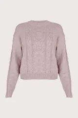 Suéter de punto color rosa con cuello redondo y mangas largas. Presenta tejido de cable al frente y a los costados, y pequeñas lentejuelas integradas en el tejido.