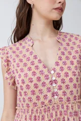 Maxi vestido de corte imperio, color rosa con estampado floral liberty en tonos fucsia. Tiene escote en V, mangas cortas con volados y falda larga con volantes. Cierre frontal con botones.