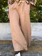 Pantalón de lino color beige, de corte ancho y tiro alto, con cintura elastizada y cinturón de soga.