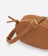 Bolso camera bag pequeño de poliuretano color negro, con forma redondeada, correa ajustable, bolsillo delantero y cierre superior.
