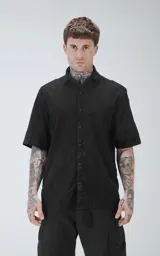 Camisa negra de manga corta con textura floral en relieve y cuello clásico.