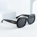 Lentes de sol negros con forma rectangular redondeada y protección UV400.