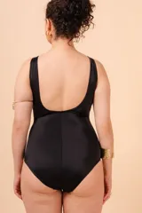 Malla entera negra con escote en V y vivos blancos en contraste. Tiene aplique de aro metálico en el cinto y bolsillo interno en el busto para colocar copa removible o prótesis externa. Confeccionada con tela que contiene fibra LYCRA® XTRA LIFE™.