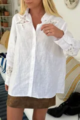 Camisa de lino blanco con detalles de encaje en las mangas y el pecho, de corte relajado.