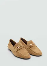 Mocasín de cuero color camel con punta fina y detalle de hebilla metálica dorada.